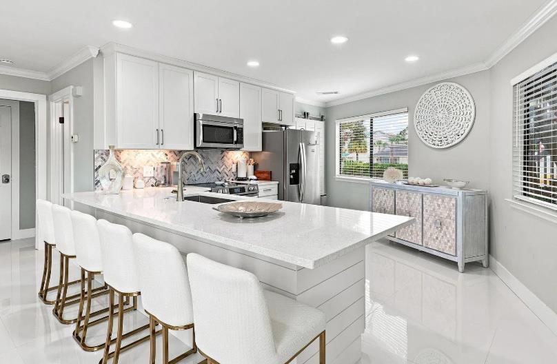 Modern kitchen featuring pristine white cabinetry, gleaming countertops, and stainless appliances.