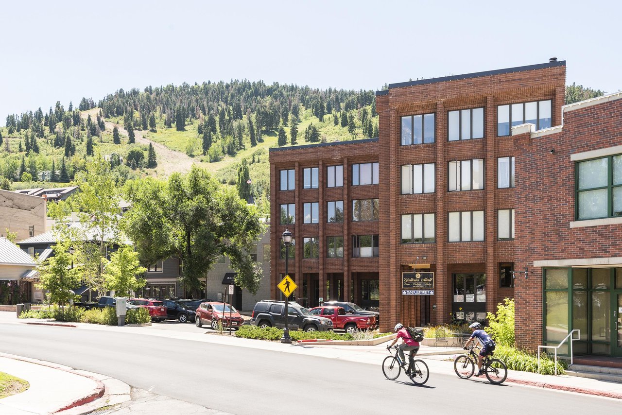 Two mountain bikers make their way up Swede Alley with Galleria in the background on a sunny summer day, green mountainside