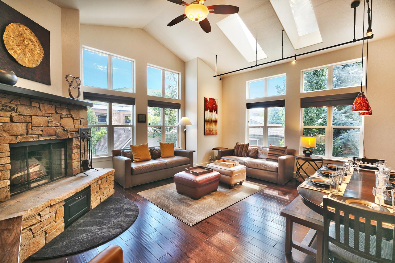 Expansive living room and dining room with track lighting and abundant natural light with two window walls