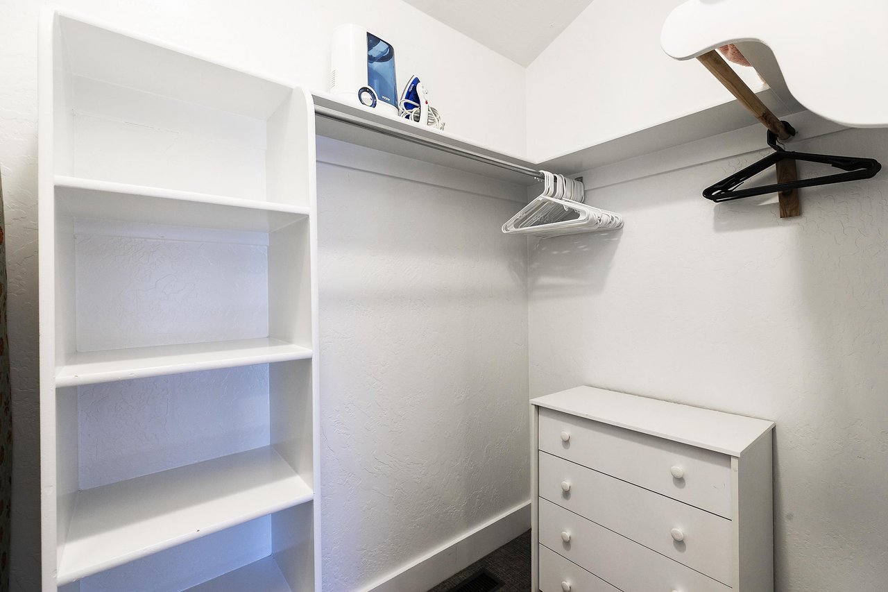 Spacious walkin closet in the main bedroom with built in cubbies, dresser, and racks