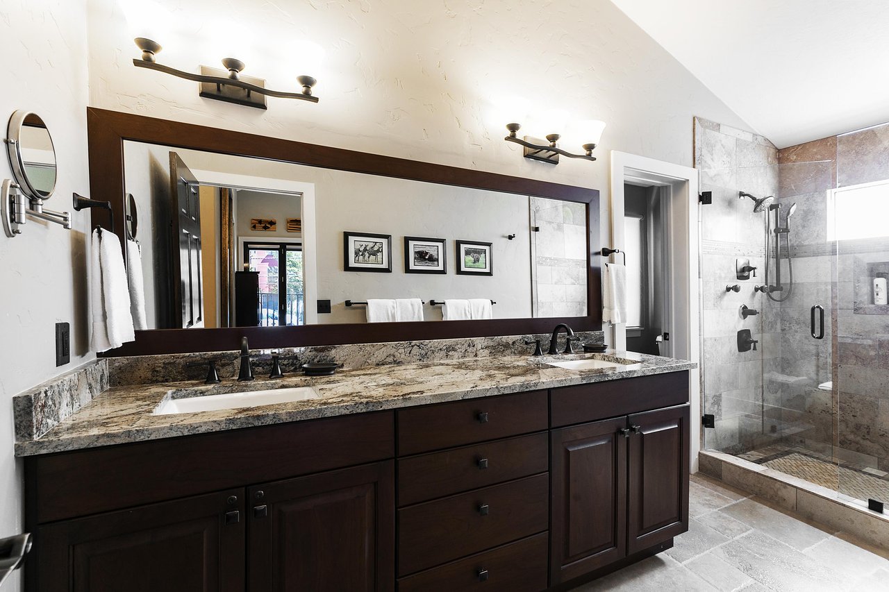 Ensuite main bathroom with granite countertops, dual vanity, glass shower door