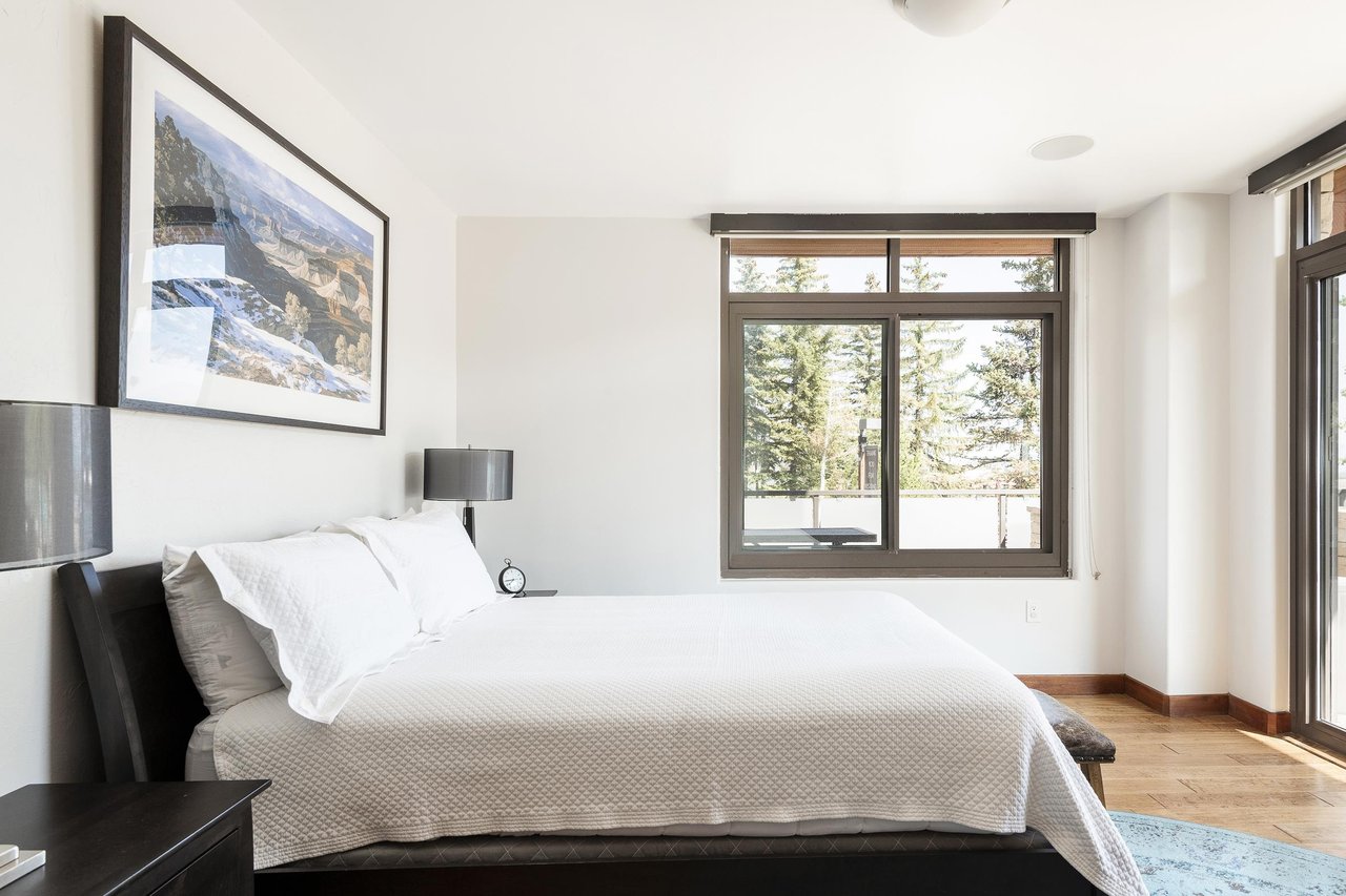 Second bedroom king bed draped in white linens and duvet, hardwood floors