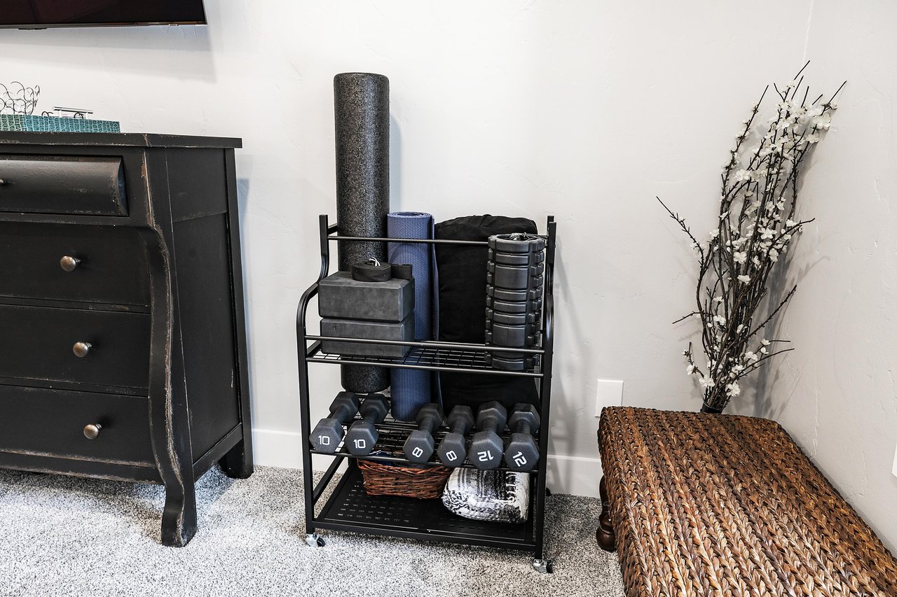 Exercise rack with dumb bells, yoga blocks and strap, yoga mat, and foam rollers