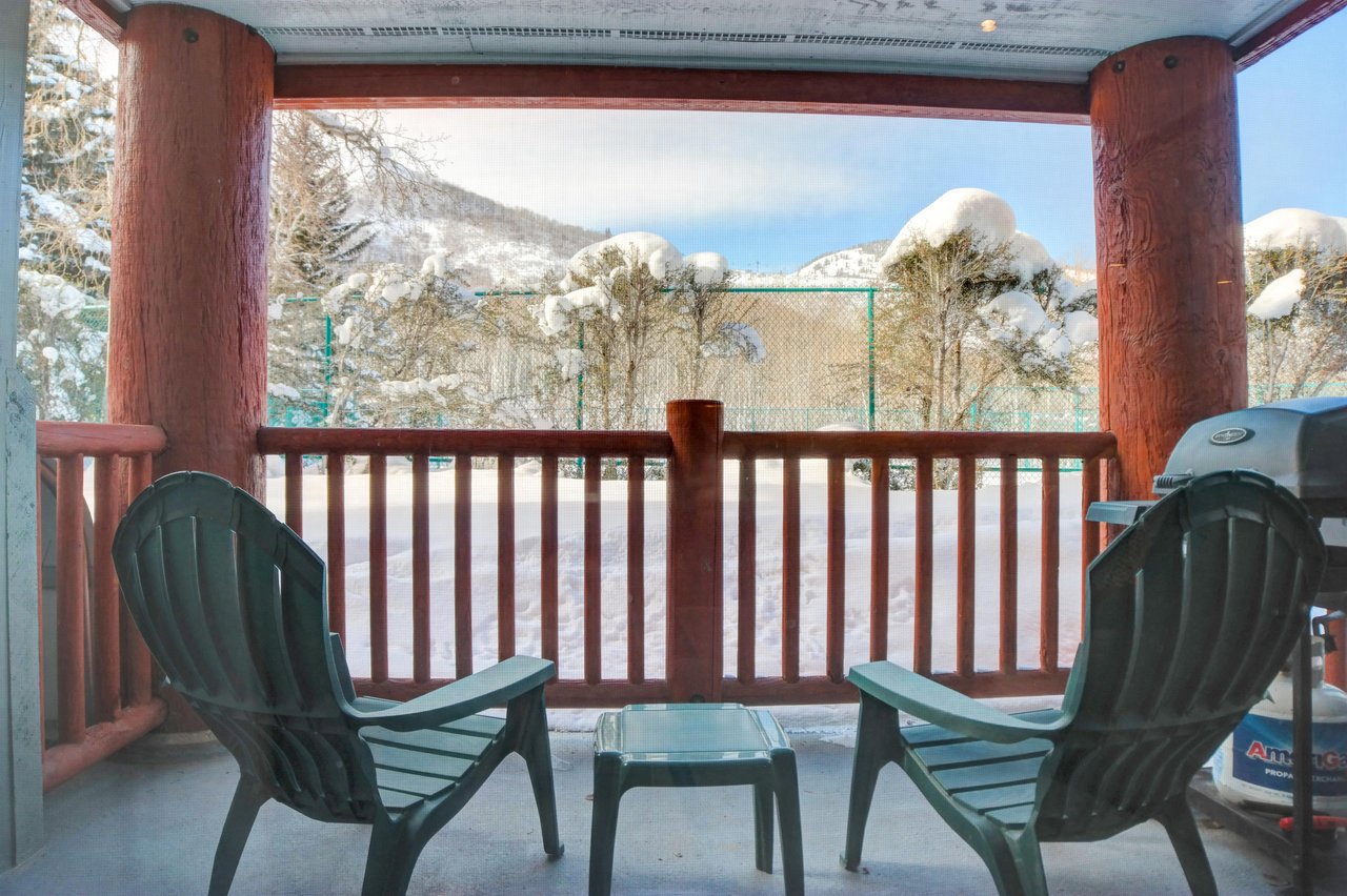 The private patio includes two green Adirondack chairs with views of the tennis courts