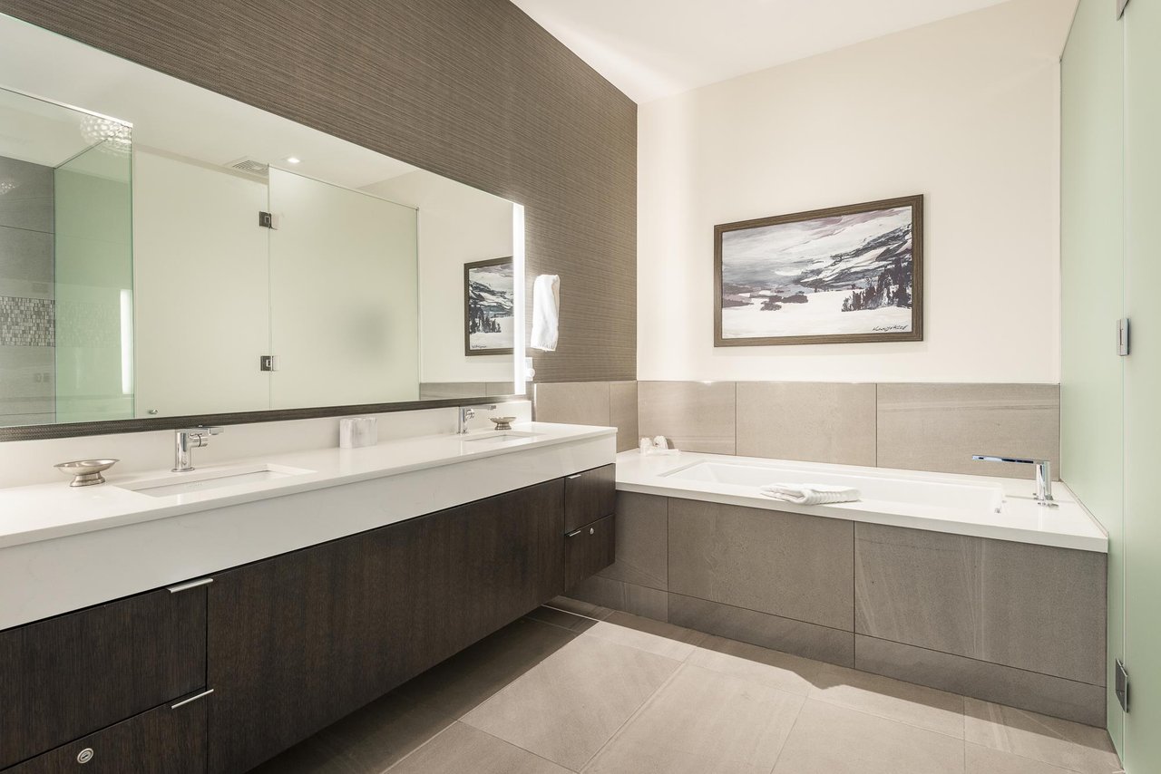 Ensuite main bathroom with double vanity, white quartz countertops and deep soaker tub