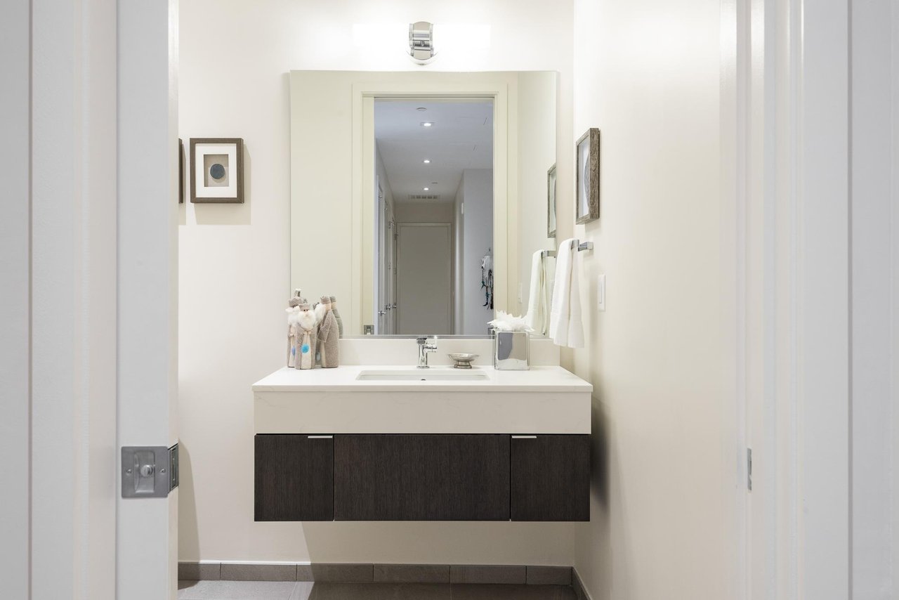 Hallway powder room with floating dark wood cabinet and white quartz counter