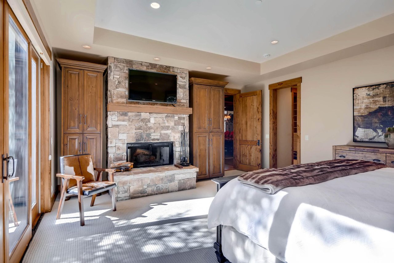 Main bedroom suite with wood burning fireplace, mounted flat screen TV, and cowhide accent chair