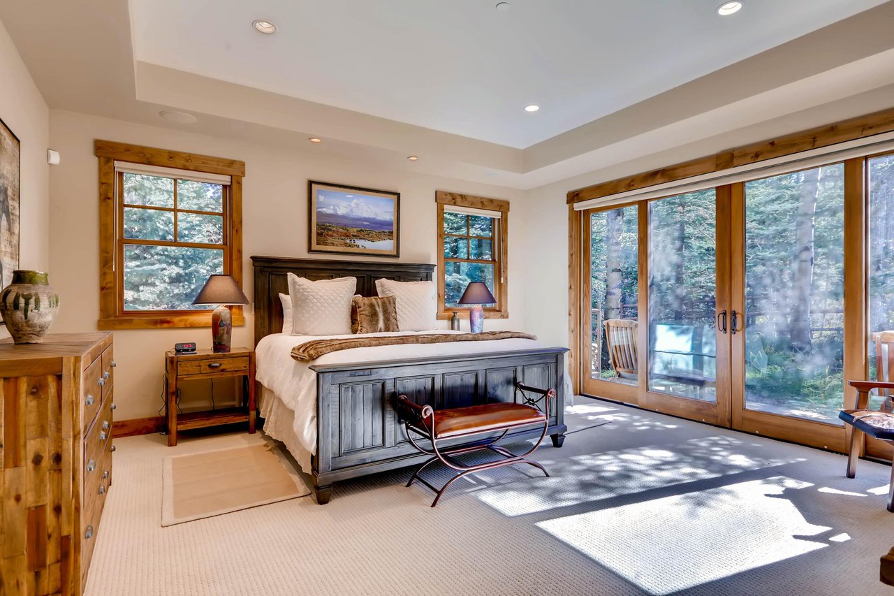 Luxurious king bed in the main suite with beautiful window walls and sliding doors to access private patio