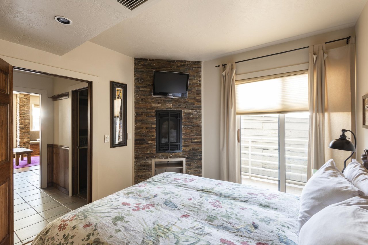 Sliding glass private balcony door in the bedroom, slatestone inroom fireplace and fireplace mounted flat screen TV