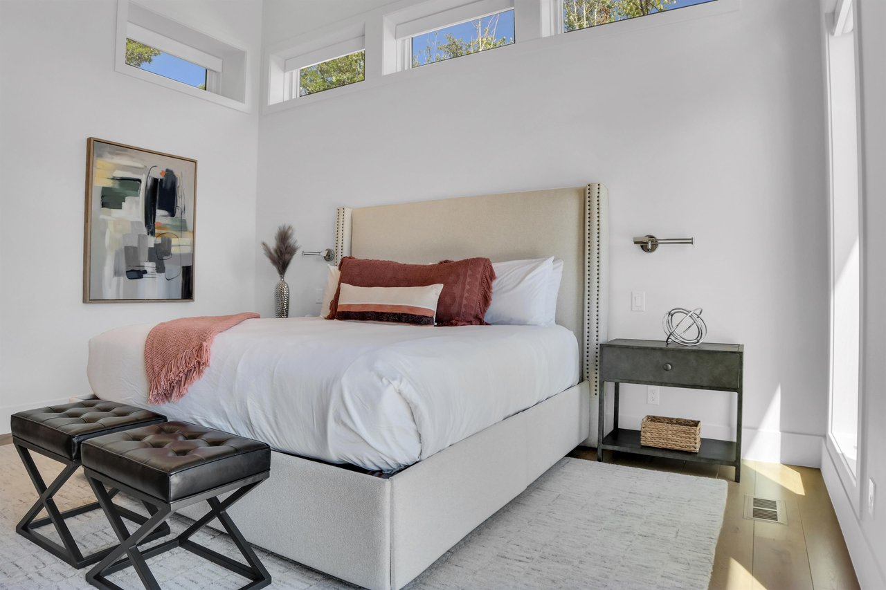 Vacation rental main suite with wood end night stands and leather stools at the end of the bed.