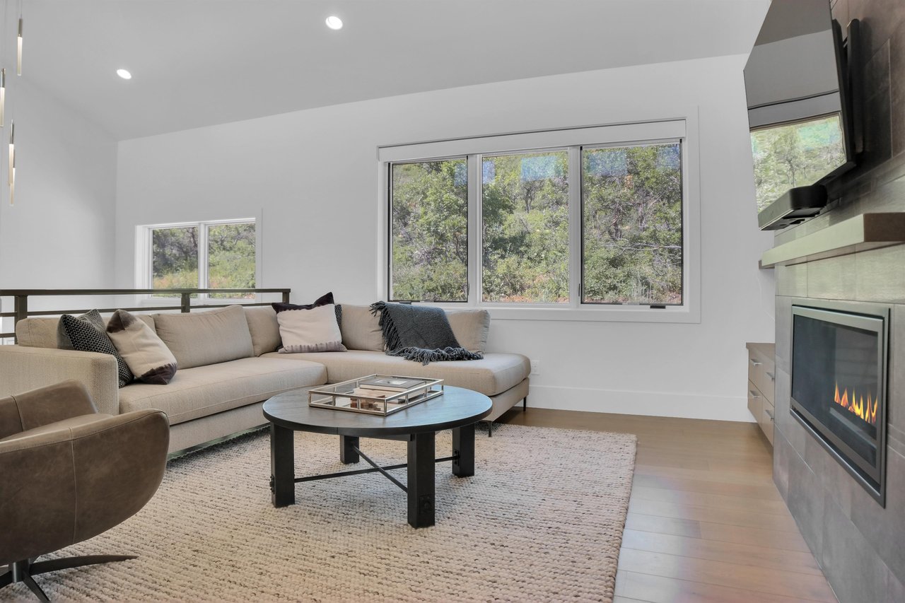 Vacation rental second living room with light grey sectional sofa and views of the surrounding hillside of oak trees.