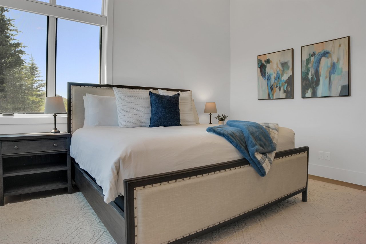 Vacation rental bedroom with a king size bed, solid wood end tables and modern art.