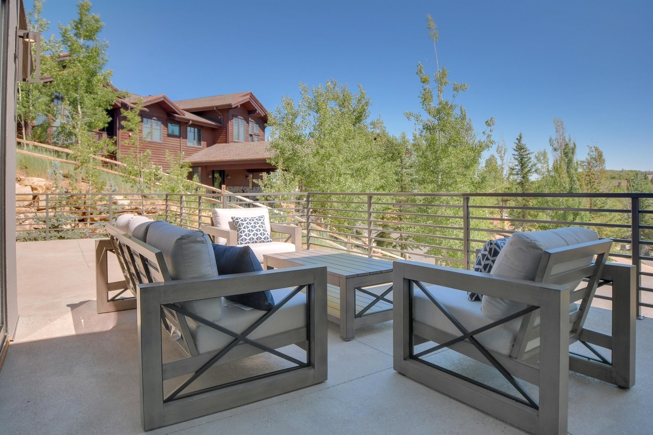 Vacation rental spacious deck with seating for six on light colored and comfortable patio furniture.