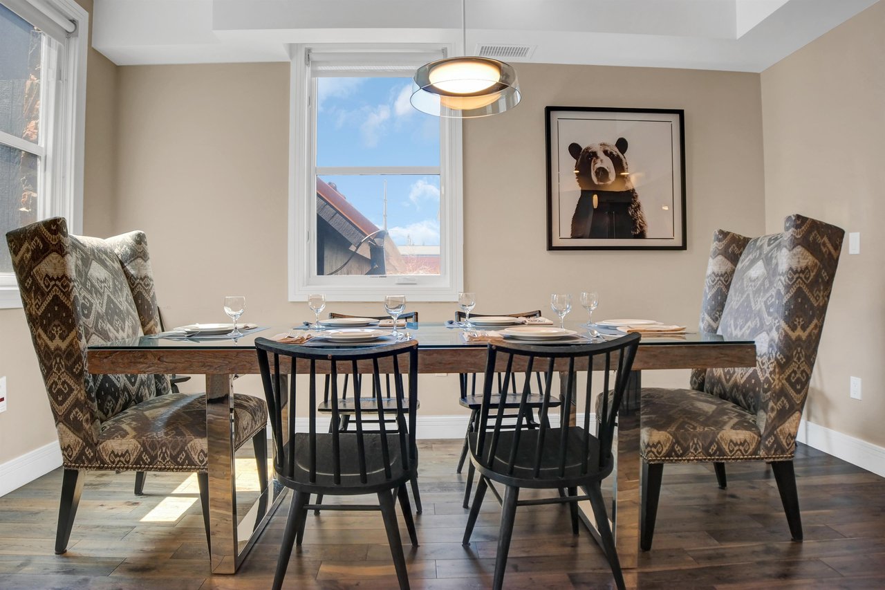 Comfortable upholstered chairs at the head of a wooden table and four black wooden chairs.