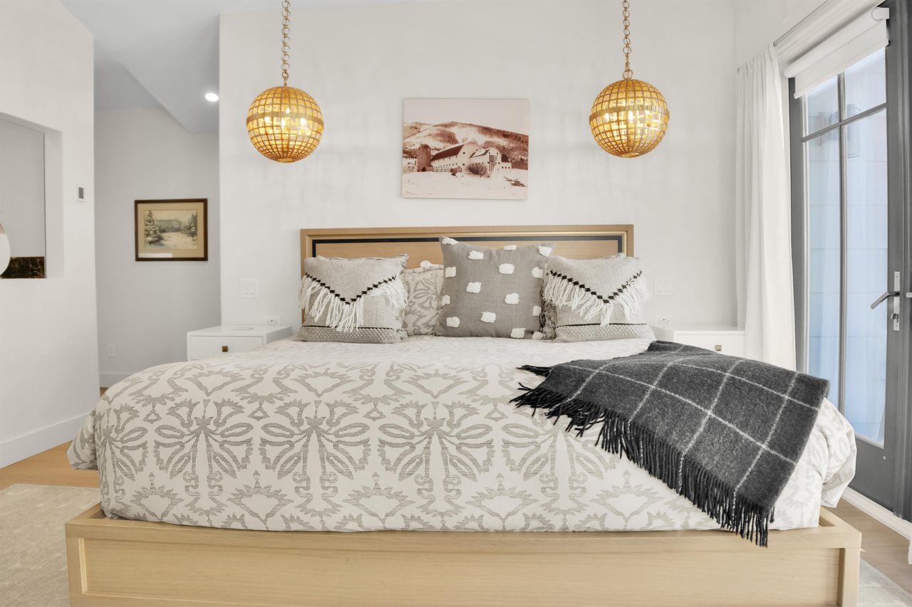The main suite king bed has two globe pendant lights hanging on each side and a sepia toned picture above the headboard.