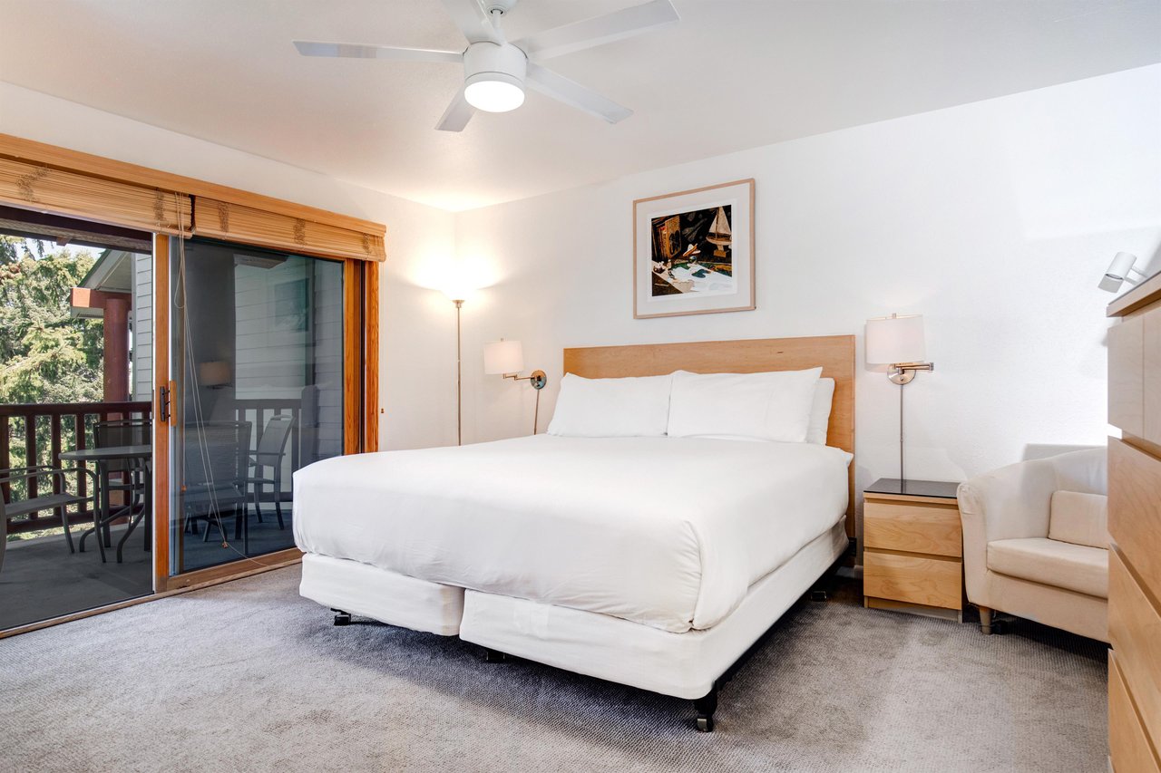 Snow Flower 29s main suite king size bed with wooden headboard and large sliding glass doors leading to a covered patio.