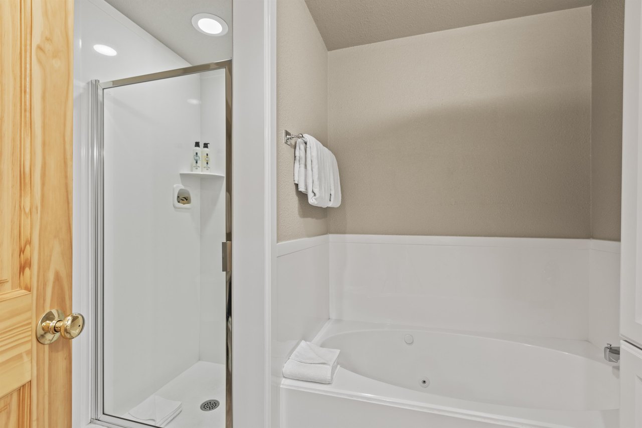 Snow Flower 72s bathroom with greige walls, white built in bathtub, and white walk in shower.