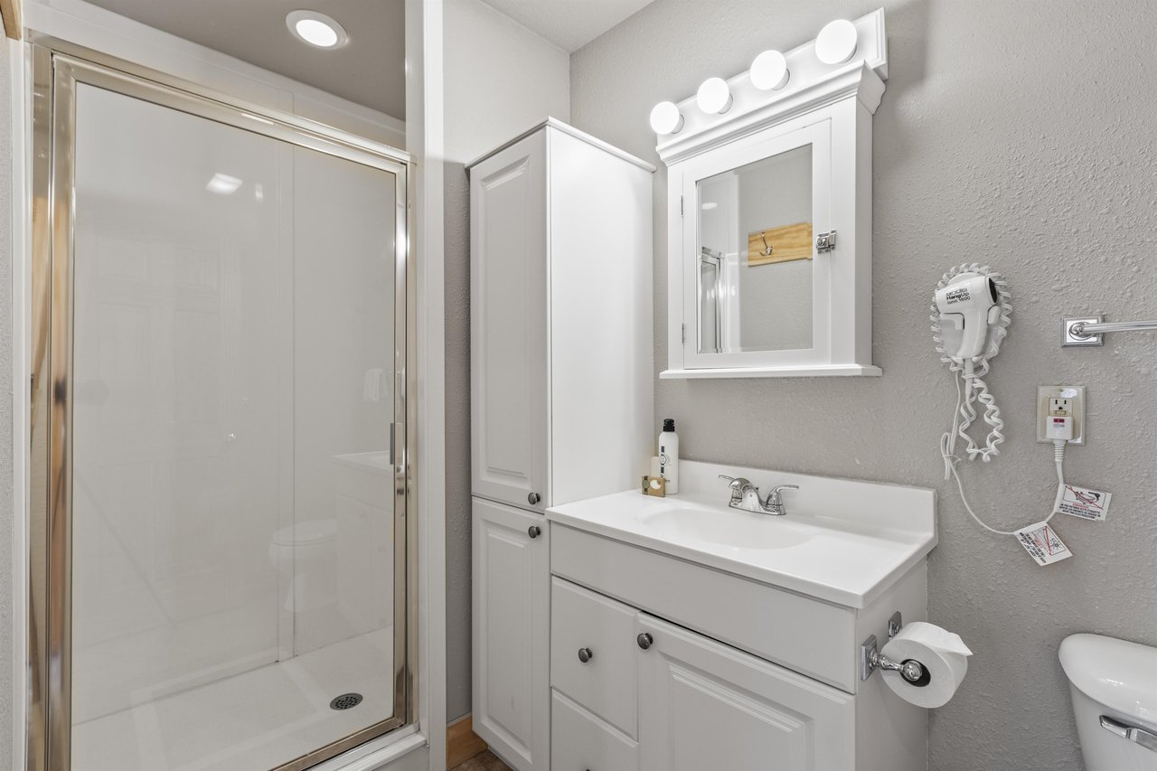 Snow Flower 72s bathroom with greige walls, white cabinets, and white walk in shower.