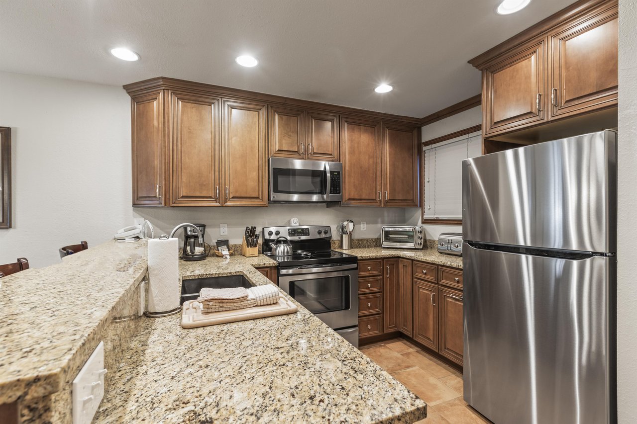 Snow Flower 135s kitchen with medium colored wood cabinets, granite counters, and stainless steel appliances.