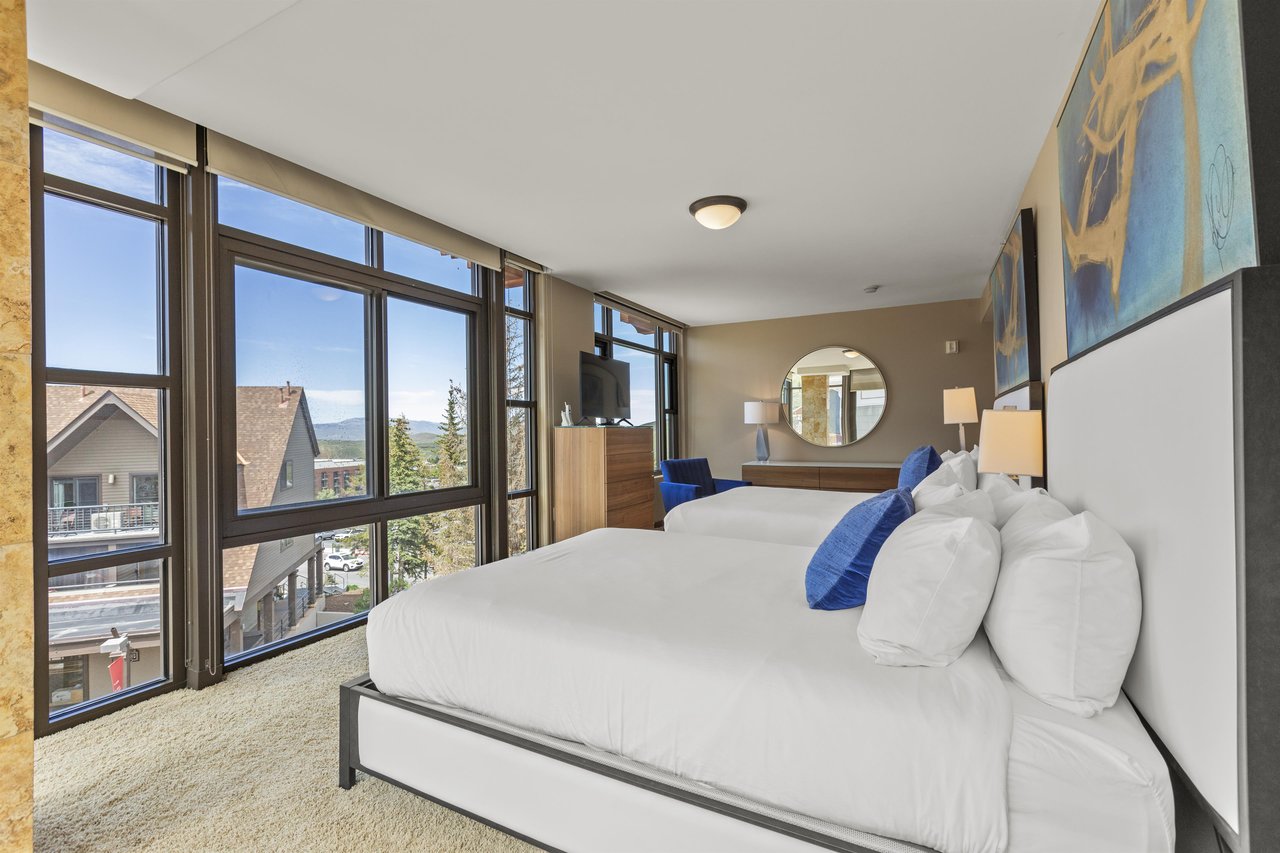 The second bedroom has two queen beds, crisp white linens, dresser, and TV.