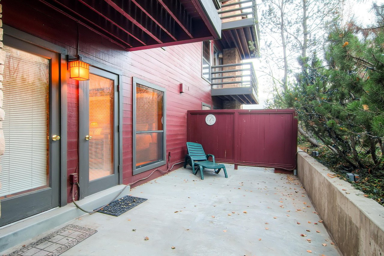 Private patio with cute red building on one side and trees adding privacy on the other side