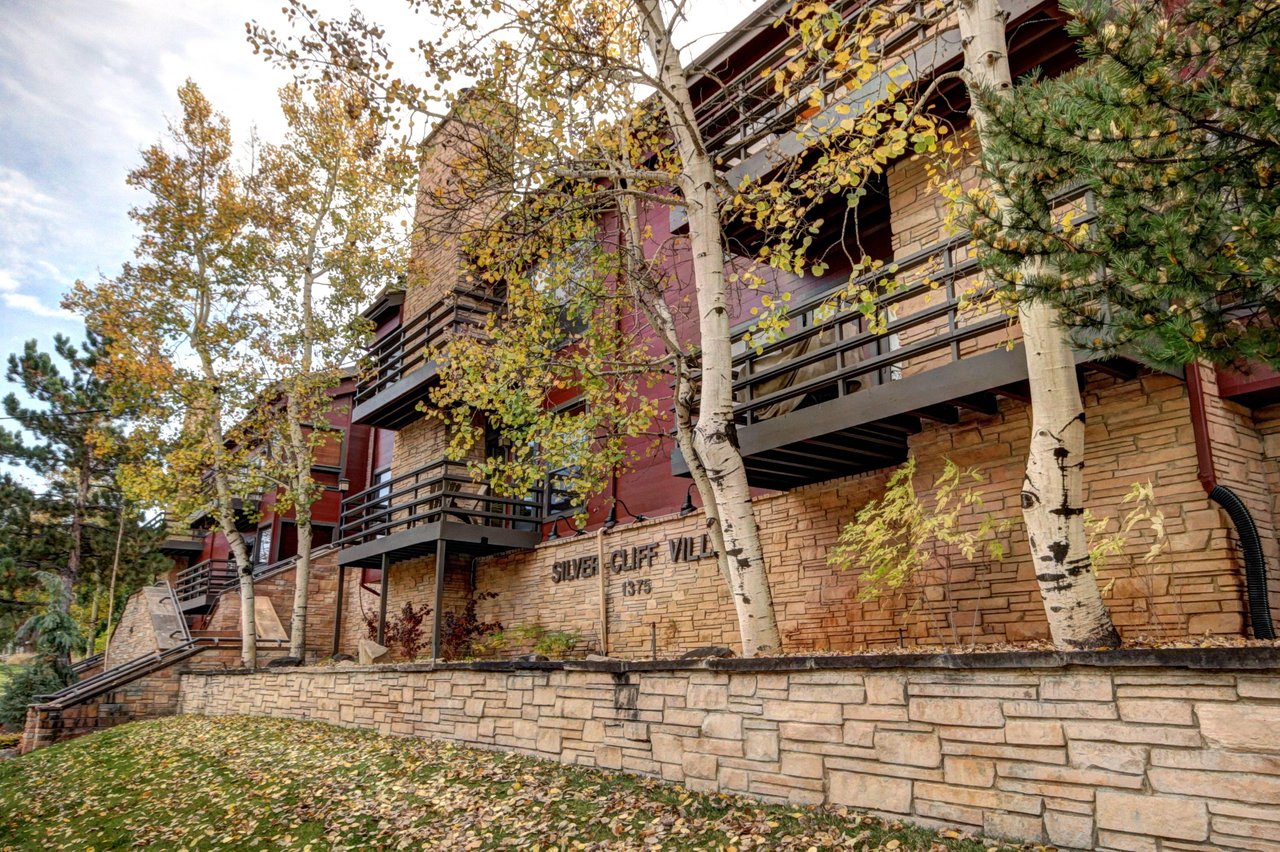 Exterior of the building, lined with a little stone wall and aspen trees