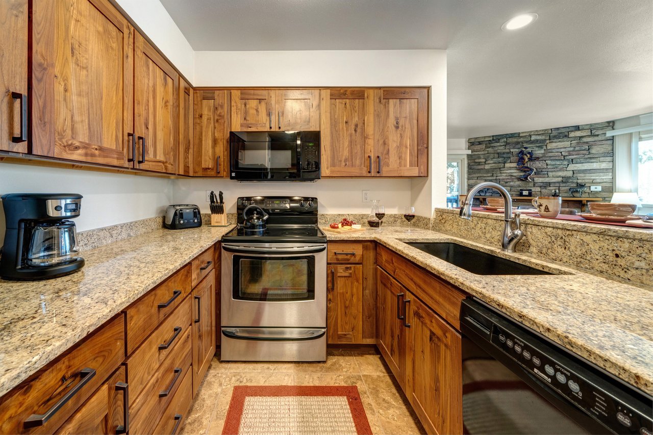 Kitchen includes granite countertops, wood cabinets, stainless steel oven and black appliances.