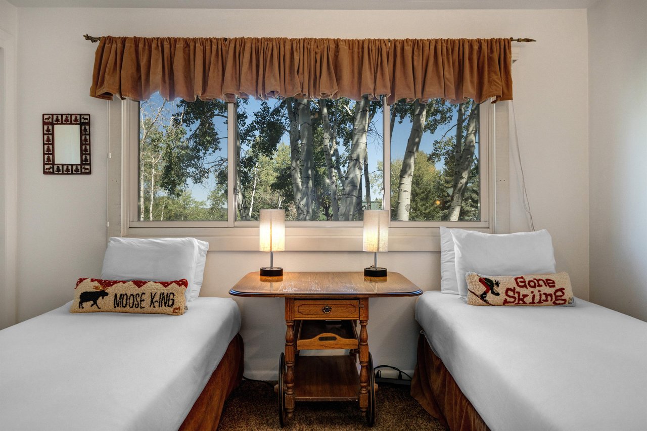The second bedroom offers two twin beds with ski pillows and crisp white bedding.