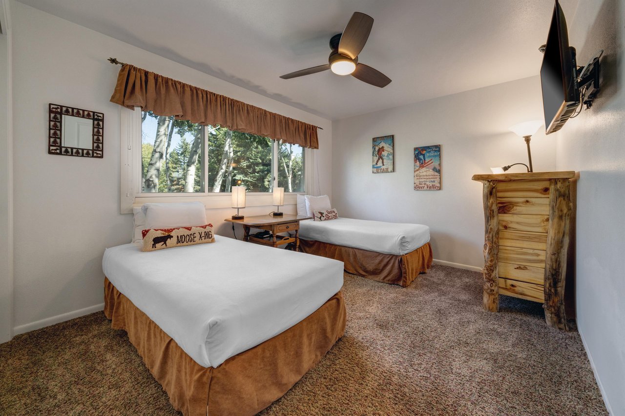 The second bedroom offers two twin beds with ski pillows, crisp white bedding and ski pictures on the wall.