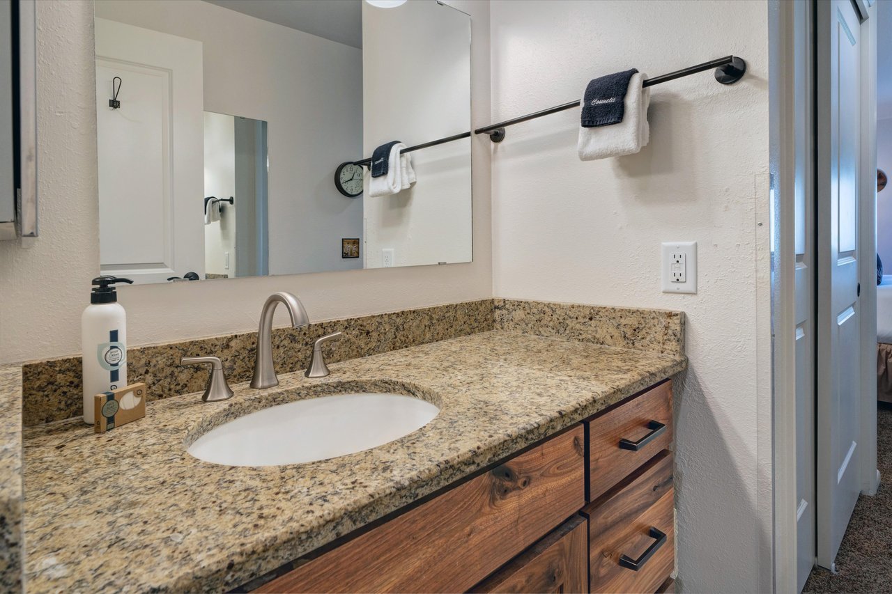 The second bedrooms shared bathroom has a  single vanity sink with granite countertop.