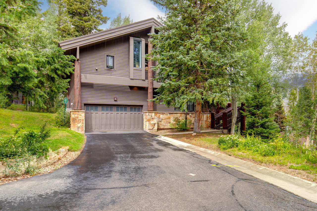 The Aspen Hollow 6 exterior is surrounded by green grass, trees, and other flowering plants.