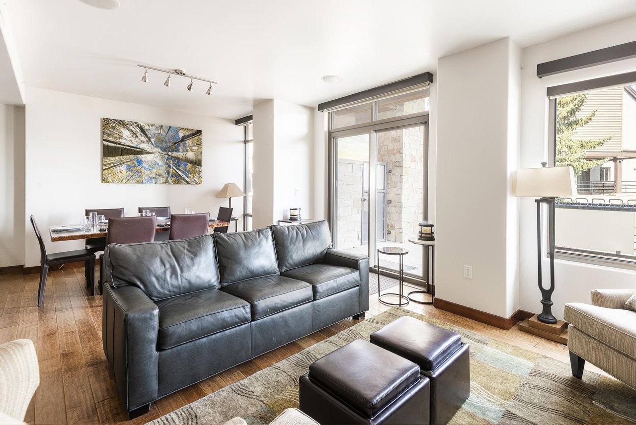 Natural light floods the living area, leather couch and foot rests