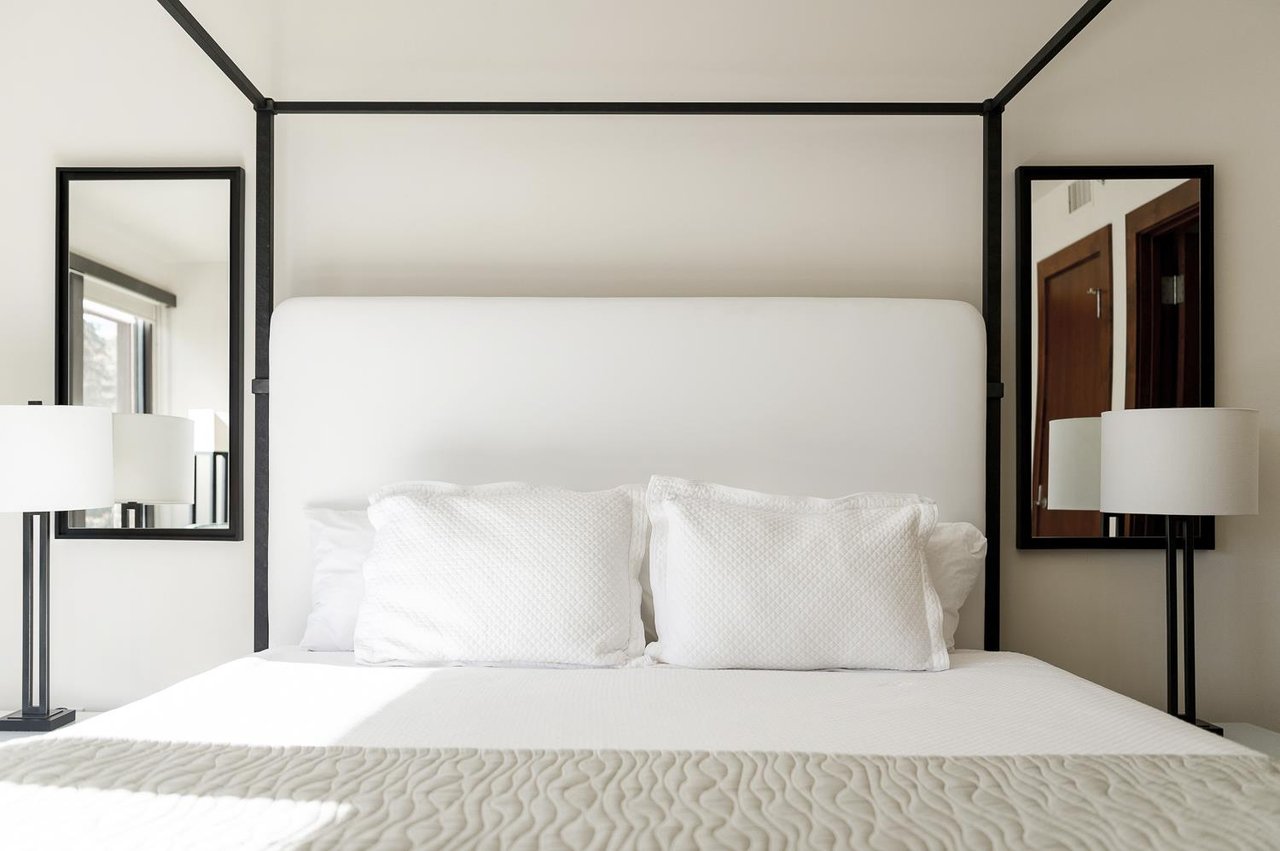Lush king bed in the main bedroom with white quilt and linens and light green quilt accent cover