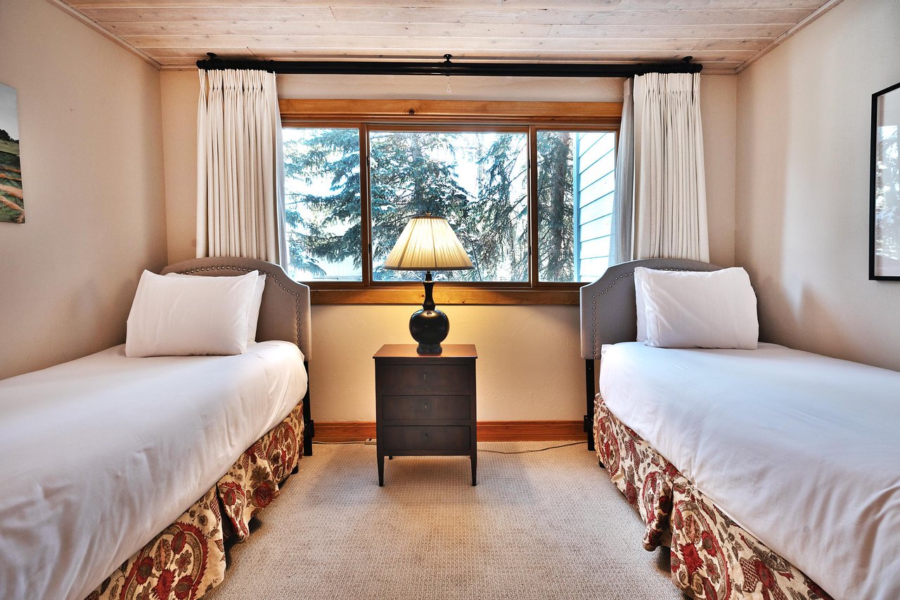 Guest bedroom features two comfortable twinsized beds with white linen