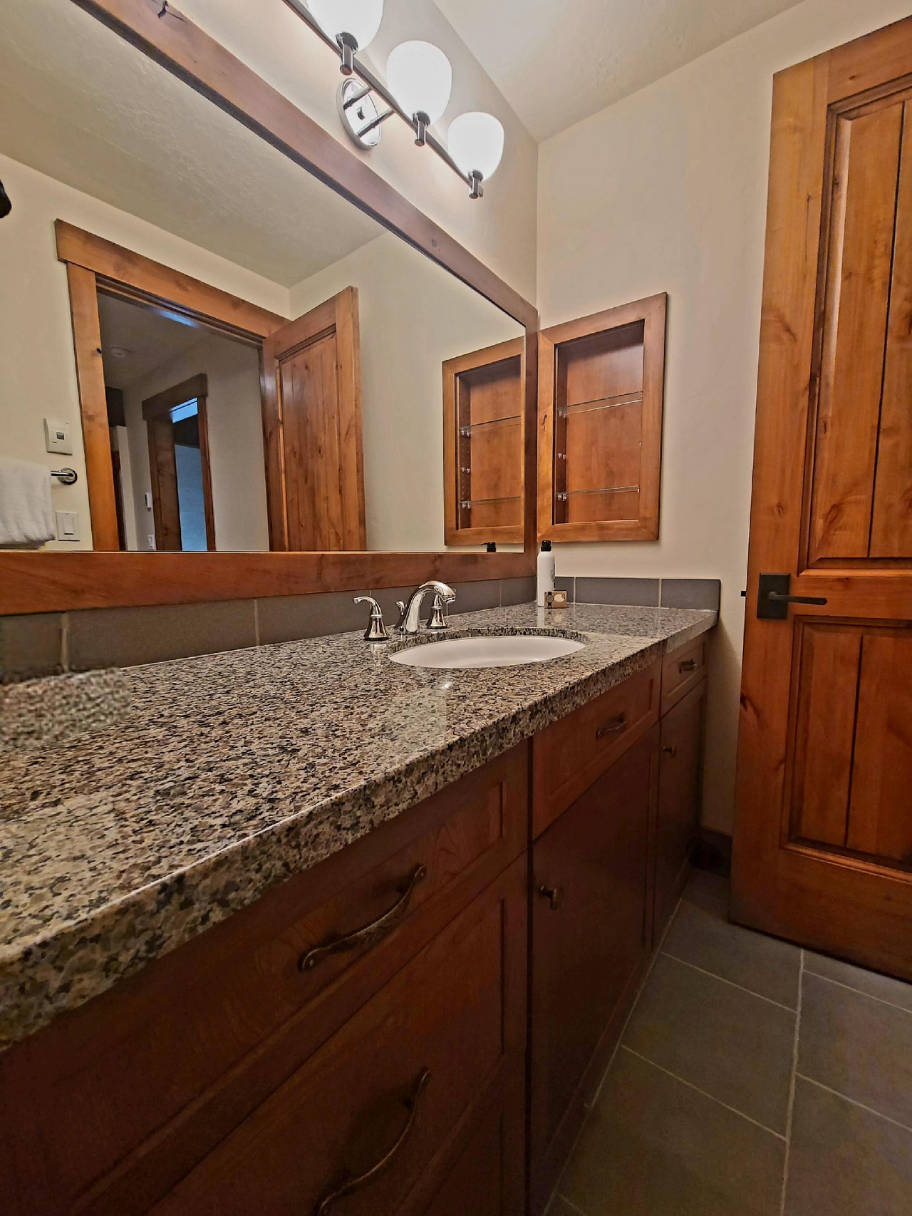 En suite fifth bathroom with gorgeous upgraded vanity with single sink with multicolored granite countertops and beautiful cabinetry