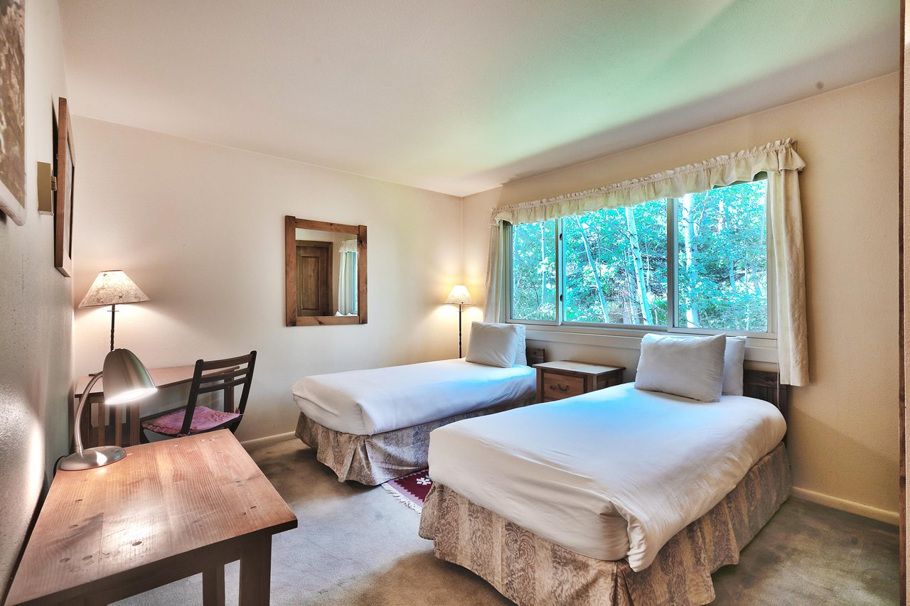 Guest bedroom with two twin beds or king bed with advance notice, work or study desk and large picture window overlooking the aspens