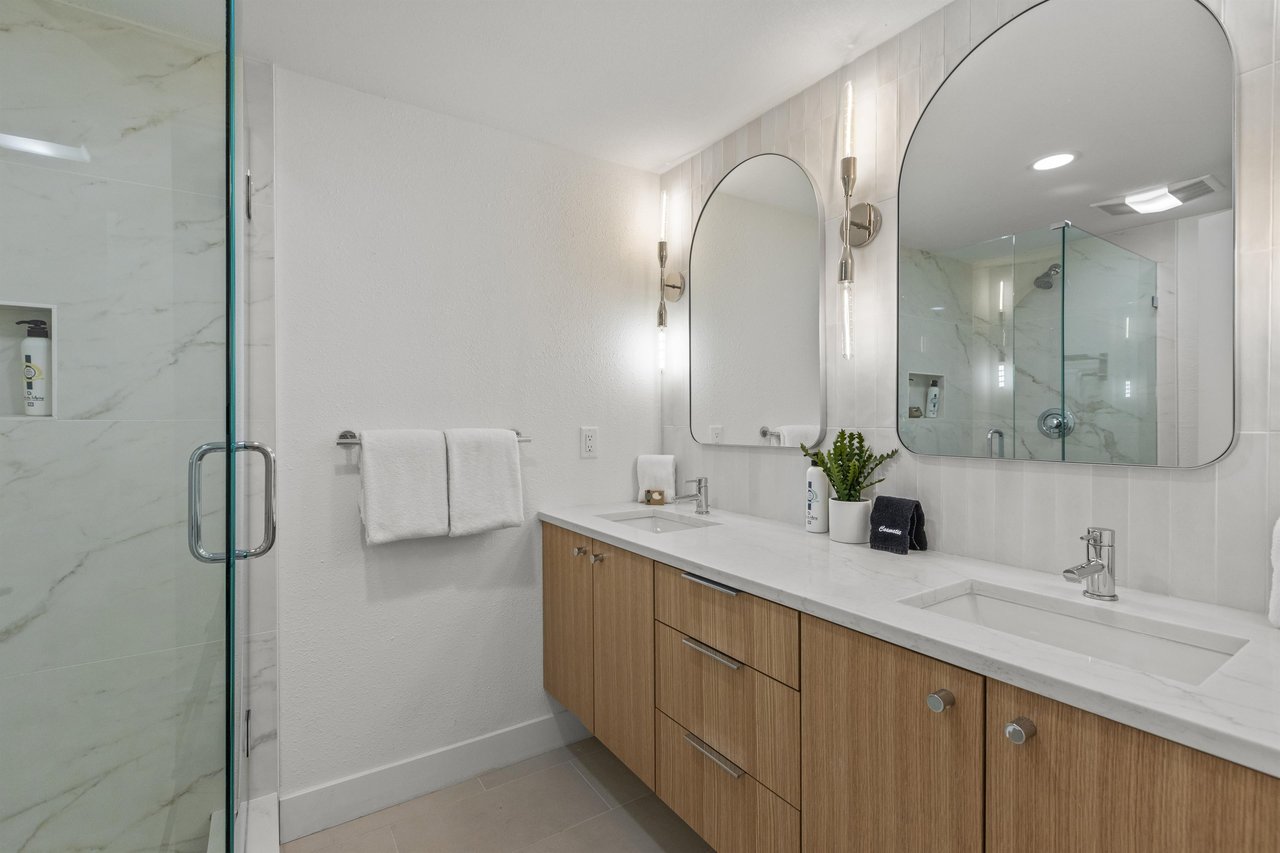 The en suite bathroom has double sink vanity, two mirrors and classic lighting.