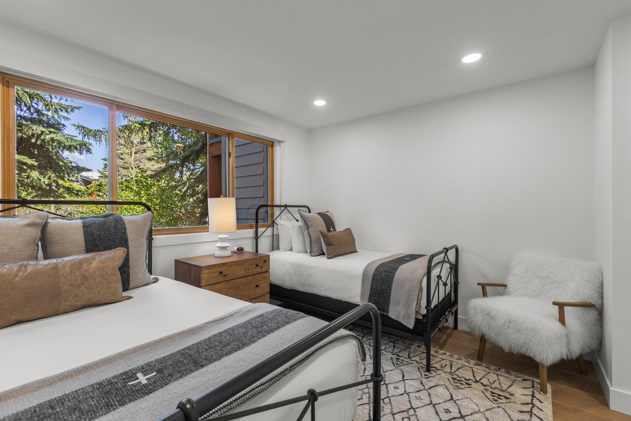 The second bedroom has a double bed and a twin bed and black bed frames.