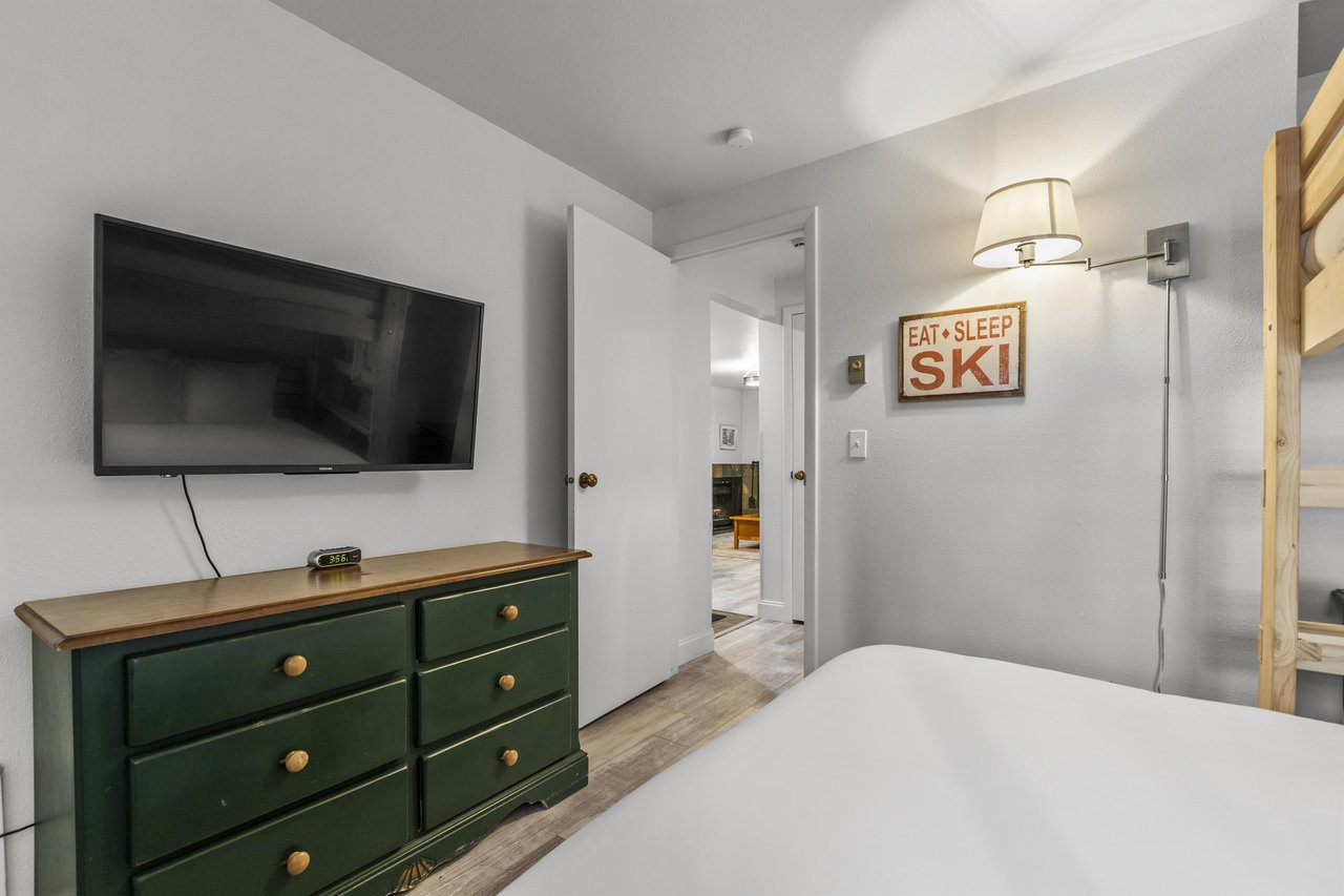 The second bedroom offers a green dresser and flat screen TV.
