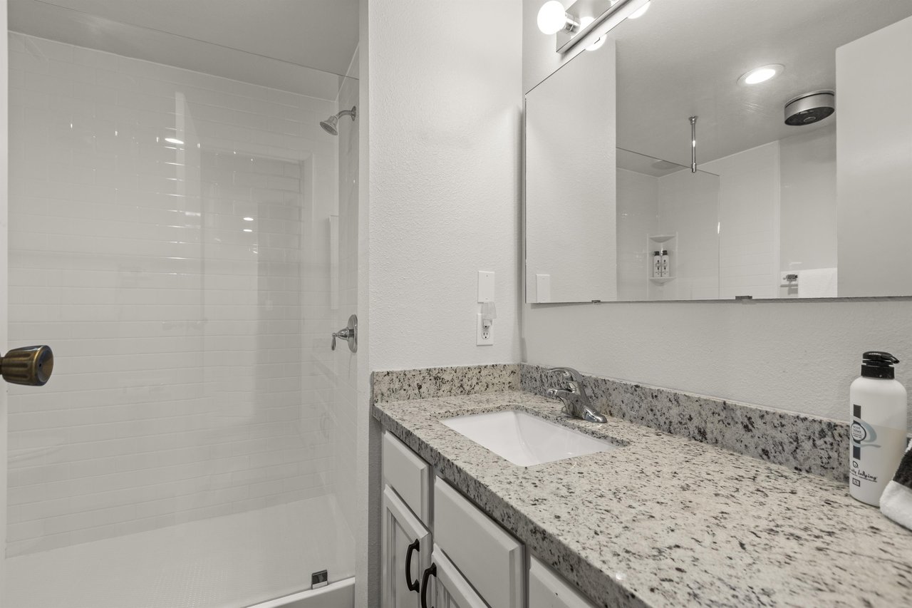 The shared bathroom offers a walkin shower and single sink vanity.