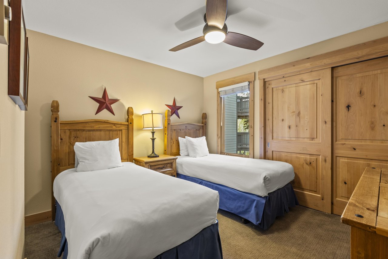 The second bedroom has two twin beds and wooden furniture.