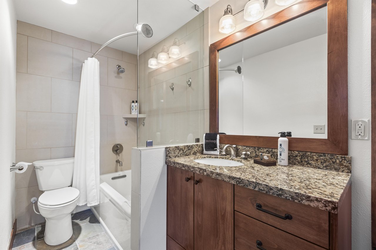 The en suite bathroom has a double sink vanity and bathtub and shower combination.