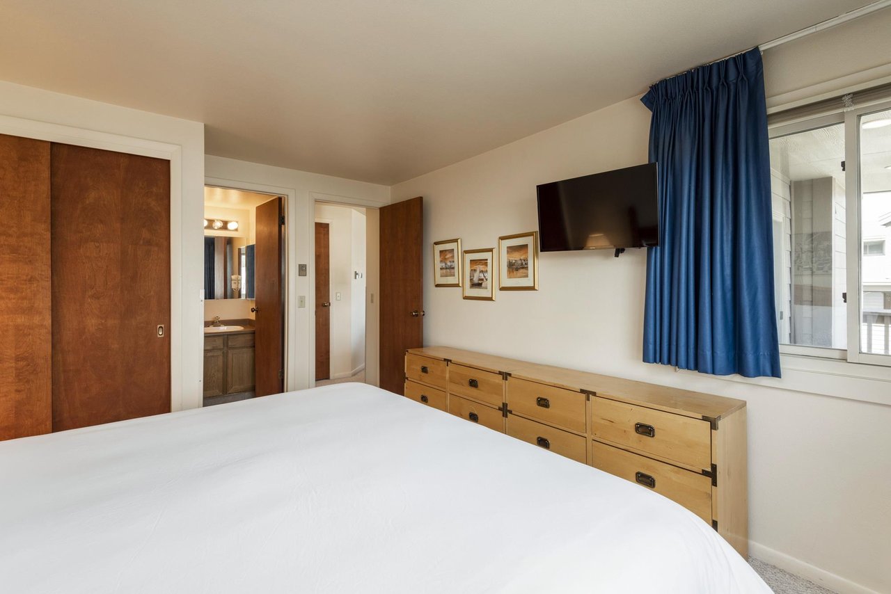 The kingsized bed in the main bedroom with wood furnishings.