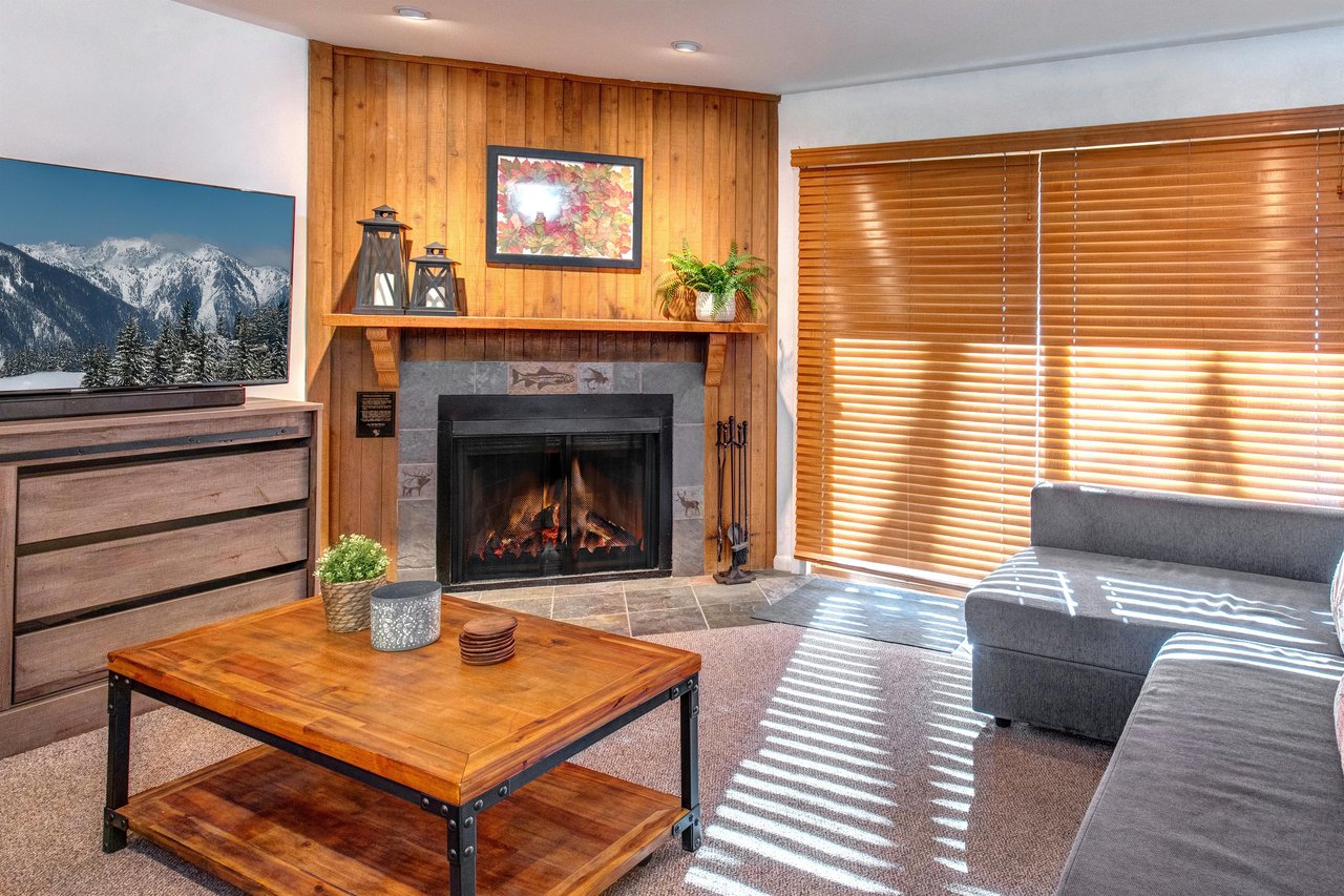 The living room has comfortable couches, gas burning fireplace and wood blinds. .