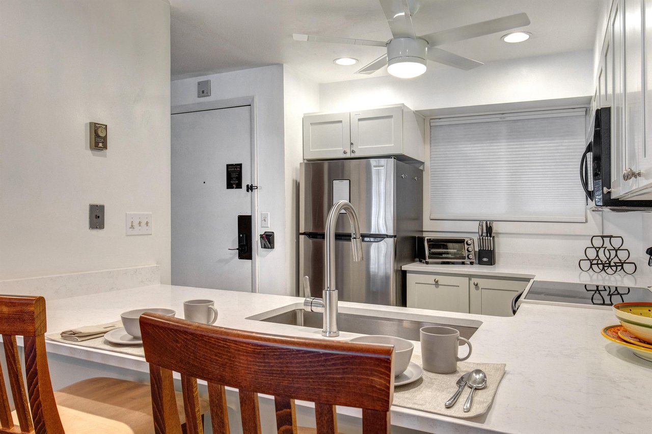 The kitchen offers a breakfast bar with seating for two guests and stainless steel appliances.