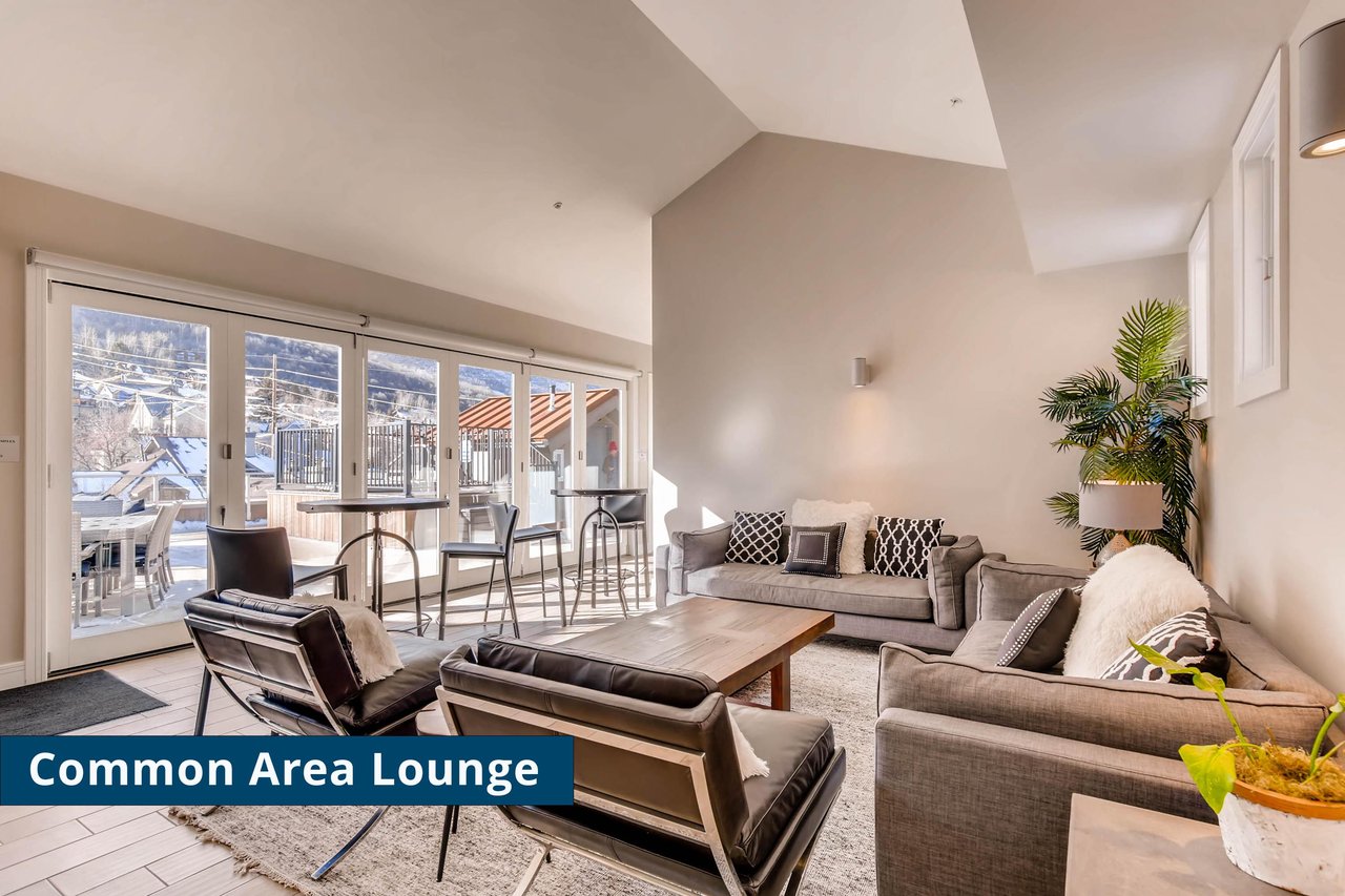 Rio Grandes common area lounge with leather club chairs, grey couches and black and white pillows and wall of windows.