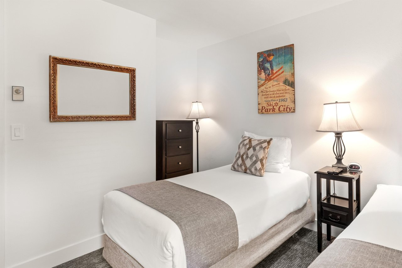 The second bedroom has two twin beds and tall dresser.
