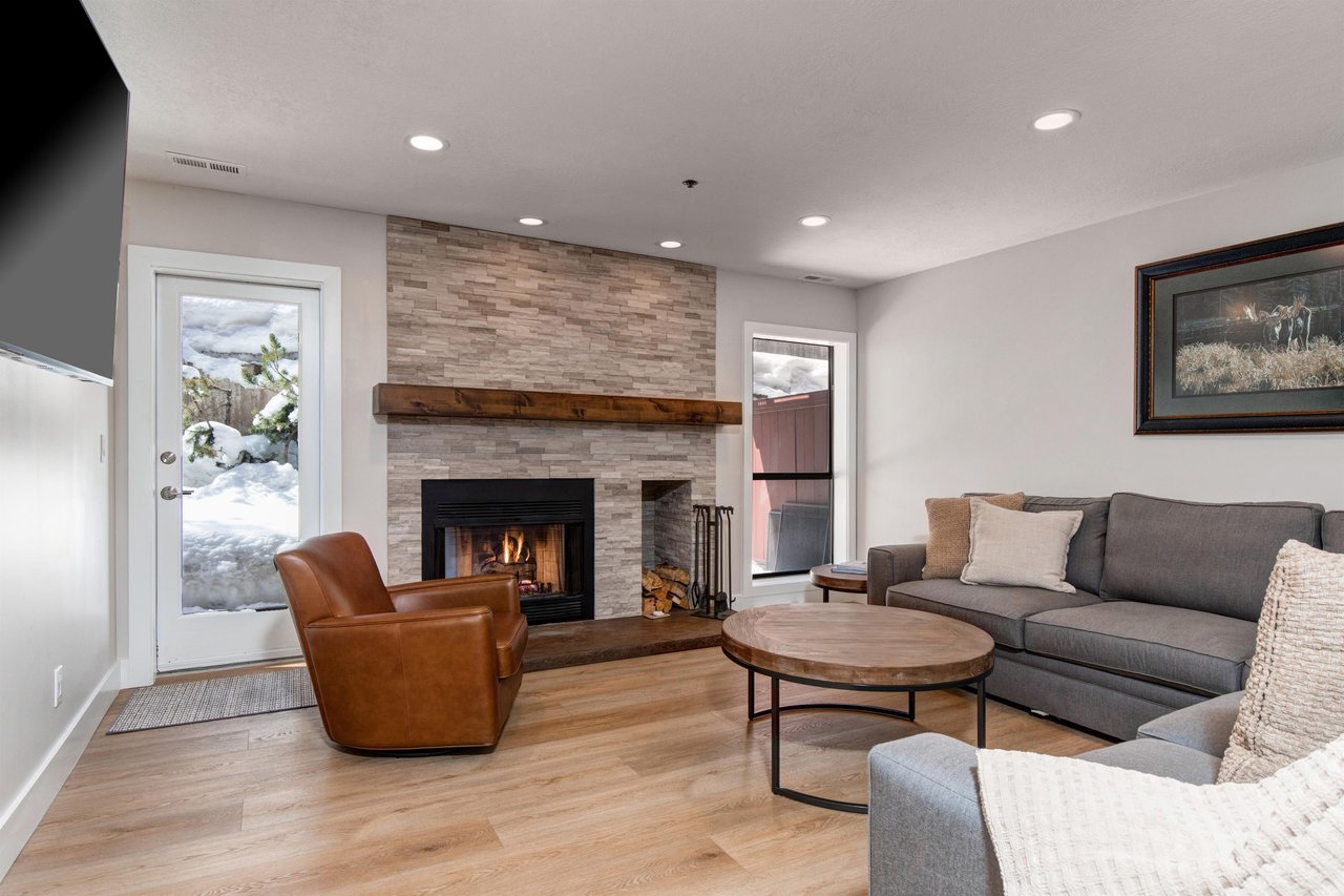 The living room offers a leather chair, grey sectional sofa, and gas burning fireplace.