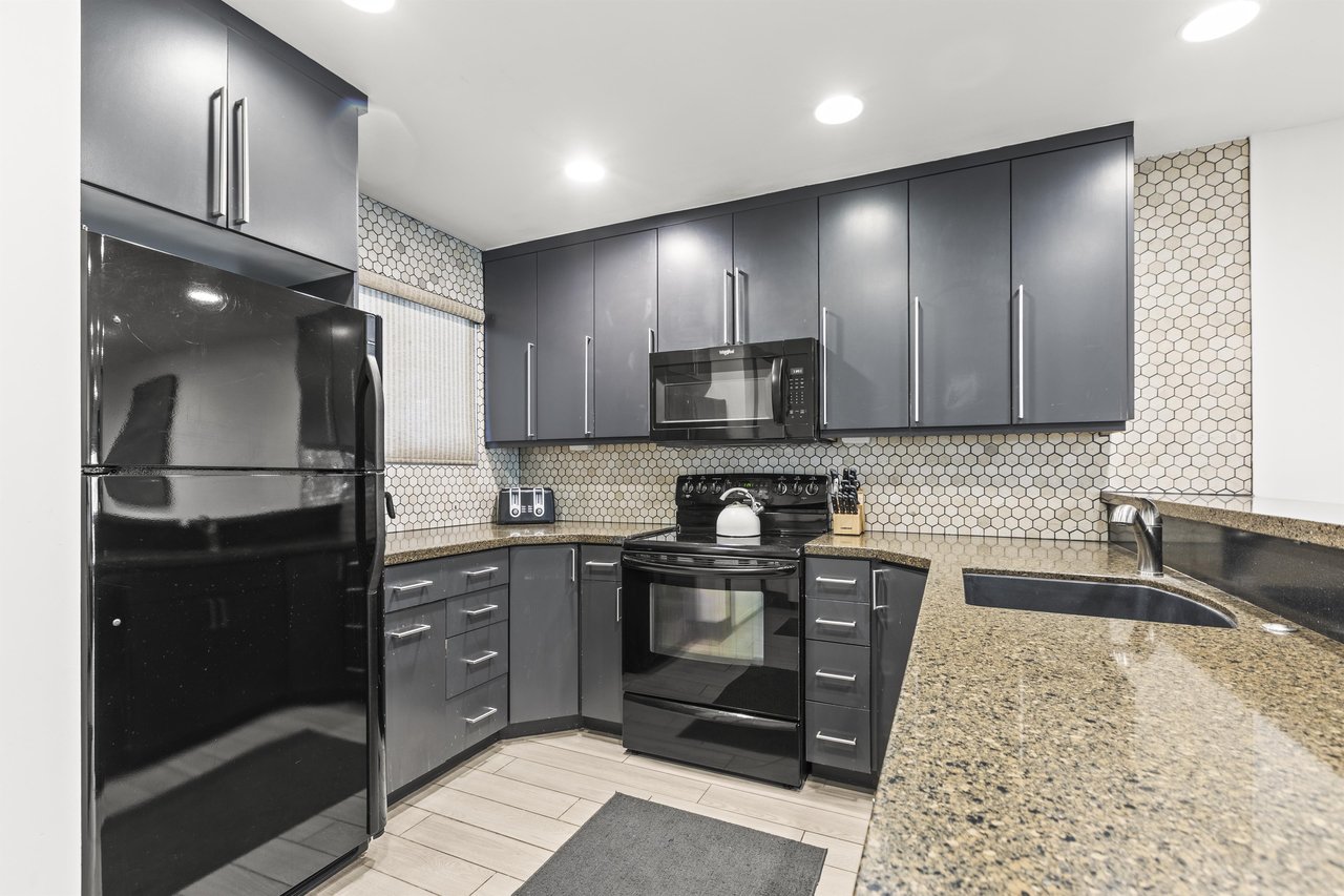 Snow Flower 126 offers a well equipped kitchen with grey cabinets, granite countertops, and tiled backsplash.