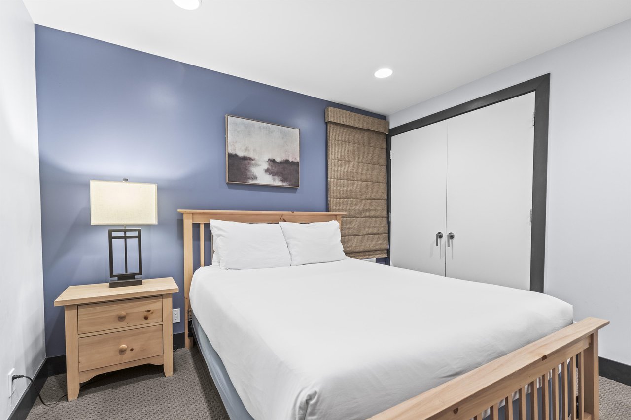 The second bedroom has a queen size bed and light wood furnishings.